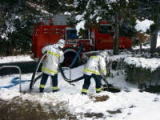 雪の中防火水槽から水を吸う写真